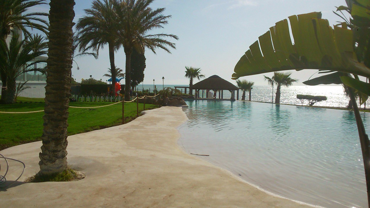 Gran piscina tipo playa junto al mar con chiringuito