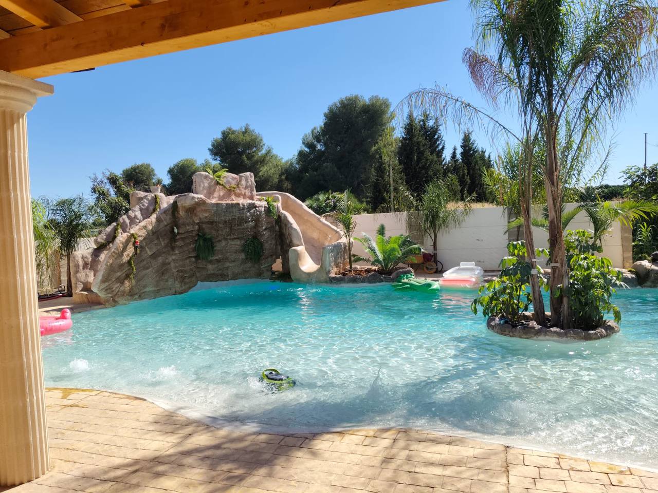Piscina con cascada y tobogán integrado en roca
